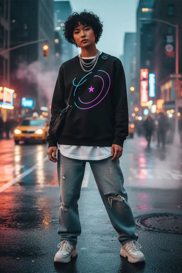 Person wearing a black sweatshirt with colorful designs on a city street at night.