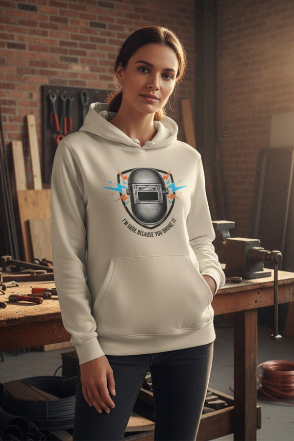 Woman wearing a hoodie with a welding helmet graphic in a workshop setting