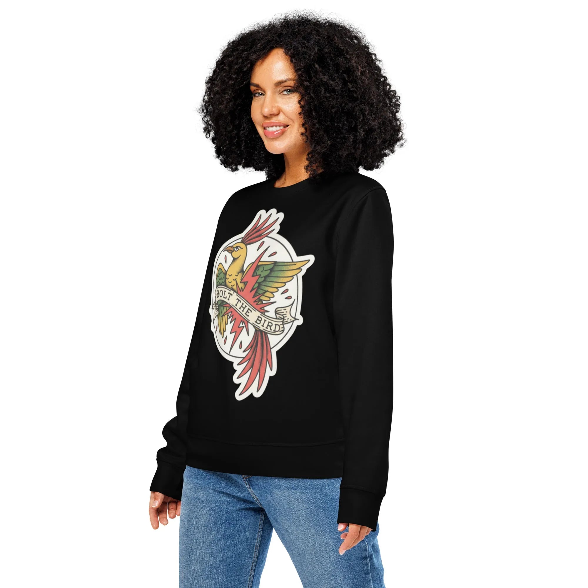 A faded blue organic cotton sweatshirt with a distressed bird graphic, draped over a worn wooden surface. Harsh, direct sunli