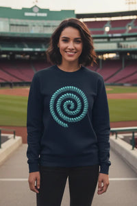 Woman wearing a navy sweatshirt with a teal spiral design at a baseball stadium.