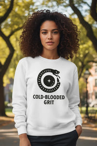 Woman wearing a white sweatshirt with 'Cold-Blooded Grit' design outdoors.