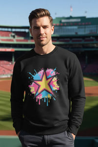 Person wearing a black sweatshirt with a colorful star design at a baseball stadium.