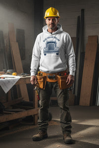 Man in a workshop wearing a hard hat and tool belt, with a hoodie featuring a truck design.