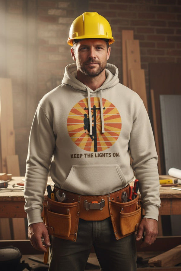 Man wearing a hoodie with a graphic design and a yellow hard hat in a workshop setting.