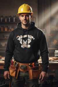 Man wearing a black hoodie with a logo and yellow hard hat, standing in a workshop.